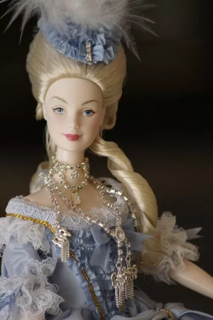 Кукла носит роскошные украшения, идентичные тем, которые вызвали скандальное "Дело бриллиантового ожерелья" в 1784 году