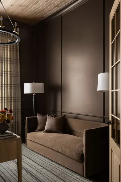 Шоколадный цвет стен отлично сочетается с коричневым диваном
